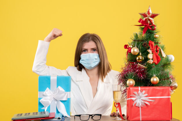 病毒正面图：戴着无菌口罩的女医生带着礼物外套年份圣诞节