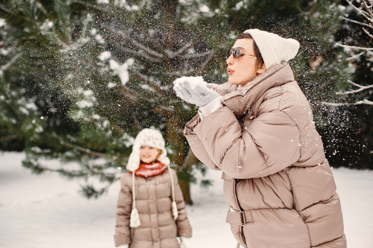 孩子一个穿着棕色夹克的女人和她的女儿在雪地公园的特写照片寒冷下雪手套