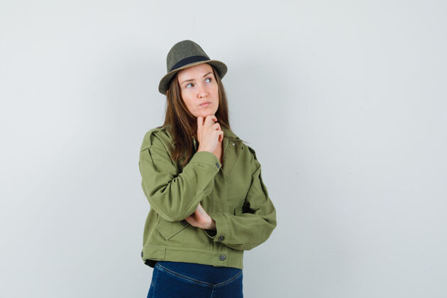 道具一位年轻的女士 穿着夹克 裤子 帽子 手托着下巴 神情沉思积极人类优雅