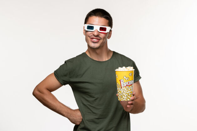 青年男性正面图身着绿色t恤的年轻男性手持爆米花包戴着d墨镜在白色办公桌上拍摄电影孤独电影院男性电影成人爆米花包装