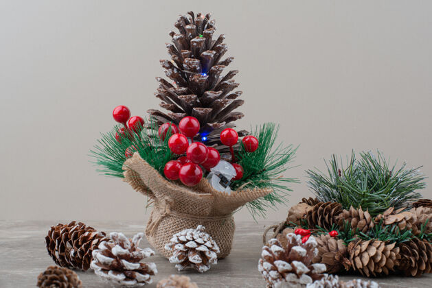 圣诞节用冬青浆果和树枝装饰的松果放在大理石桌上冬天树枝圆锥体