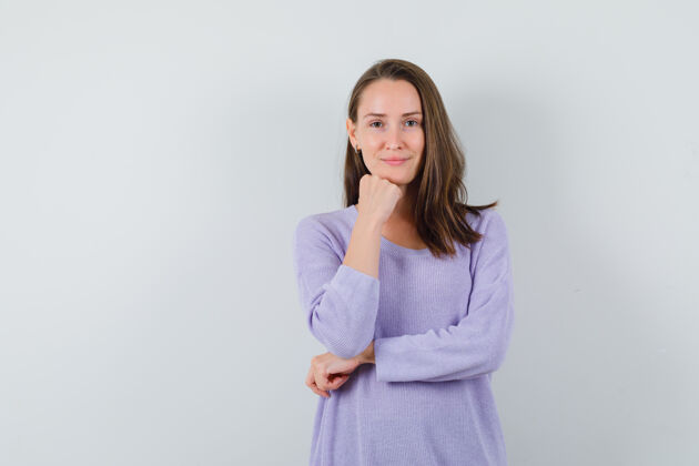 衬衫一位年轻的女性斜靠在她的拳头边对着镜头微笑 身穿淡紫色上衣 看上去很清新卷曲而自信