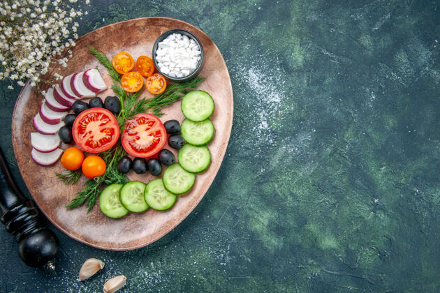 健康上图：新鲜切碎的蔬菜橄榄盐放在一个棕色的盘子里 厨房的锤子放在绿黑色混合色的桌子上锤子厨房右