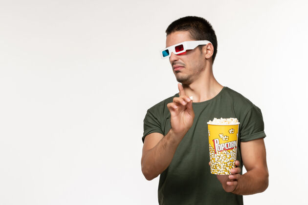 年轻男性正面图身着绿色t恤的年轻男性手持爆米花in-d太阳镜在白墙上看电影孤独电影院男电影青少年帅哥肖像