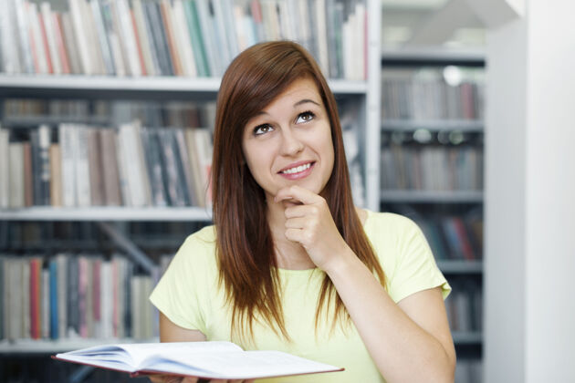 学习年轻女子在图书馆做白日梦Campus欢呼搜索