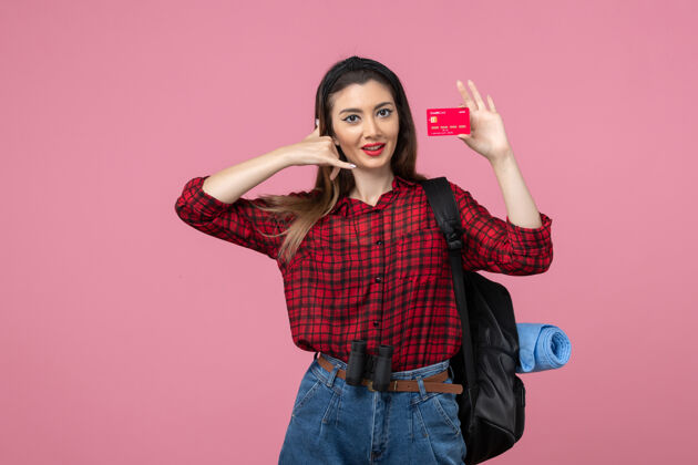 成人正面图身穿红色衬衫的年轻女性手持粉色背景的银行卡人类女性颜色肖像持有漂亮