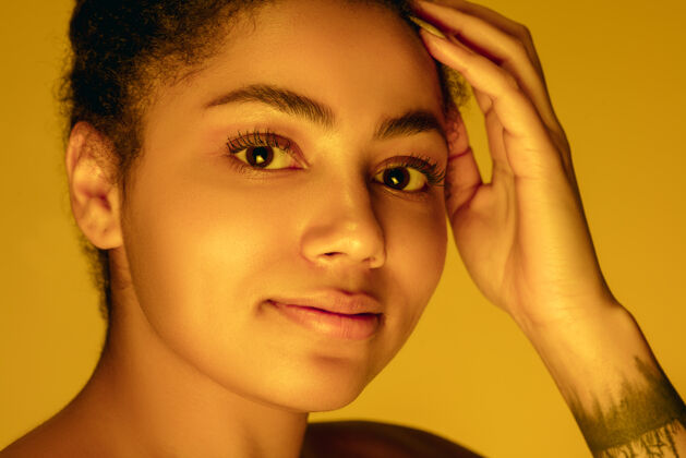 模特在霓虹灯下的黄色摄影棚上的美女肖像 单色手辉光情感
