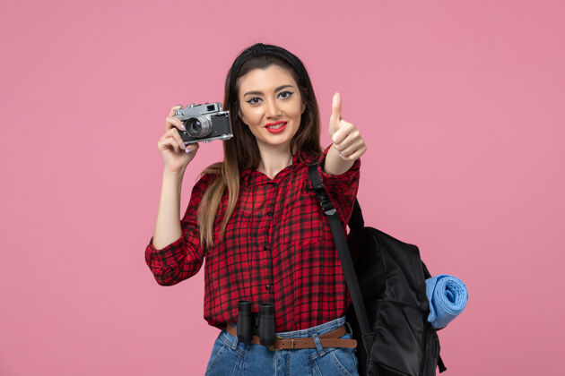 肖像正面图年轻女性用相机在粉色背景上拍照女性彩色拍摄微笑黑发