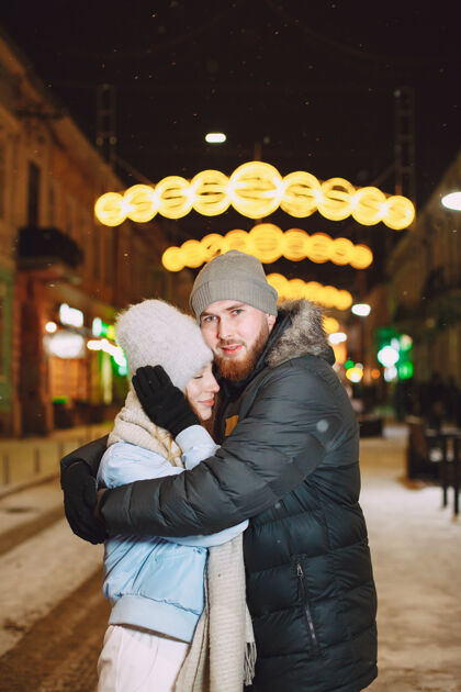 户外一对年轻夫妇在街上摆姿势的户外夜景节日城市雪