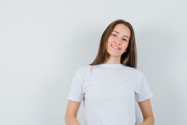 性感年轻的女士穿着白色t恤看着镜头 看上去很高兴人性化T恤连衣裙