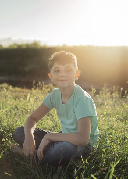 全镜头坐在草地上的全垒打小子肖像年轻垂直