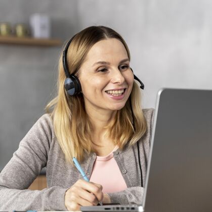 笔戴着耳机在笔记本电脑上工作的女人学习笔记本设备