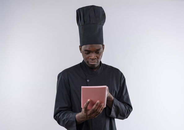 空间年轻的美籍黑人厨师身着厨师制服 拿着笔记本看着白色的复印件厨师年轻笔记本