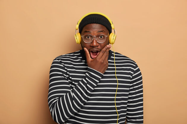 立场情绪化的黑人年轻人托着下巴 用现代耳机听音乐民族音频非洲