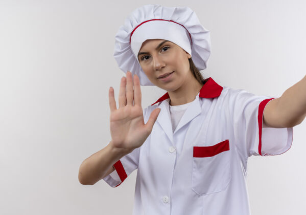 举行身着厨师制服的年轻自信的白种人厨师女孩手持相机 在白色的空白处做手势女孩信心制服