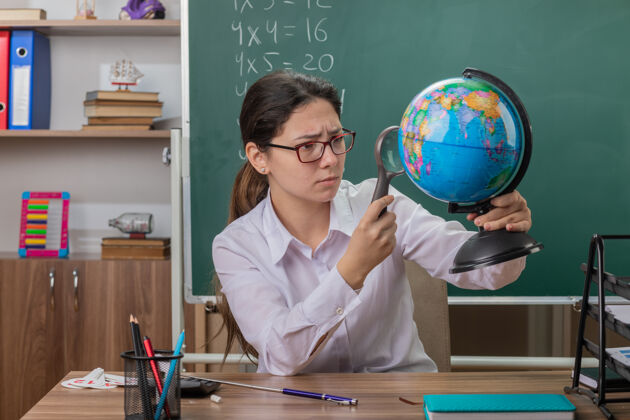 黑板戴着眼镜拿着地球仪的年轻女老师玻璃桌子自信