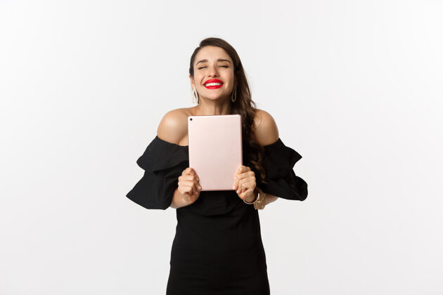 时尚时尚购物理念红唇快乐的年轻女子 身穿黑色连衣裙 手持数字平板电脑 中奖 白色背景女性年轻平板