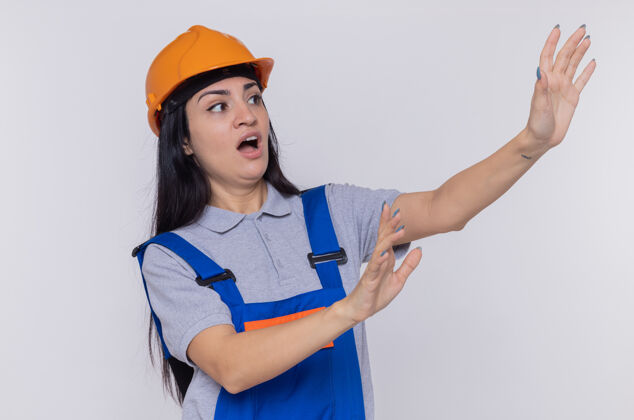 站着身穿施工制服 头戴安全帽的年轻女建筑工人在一旁焦急地看着年轻头盔建筑工人