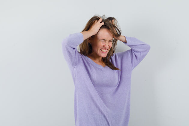 头发年轻的女性双手抱着头 穿着淡紫色上衣 看起来很有压力女性压力卷发