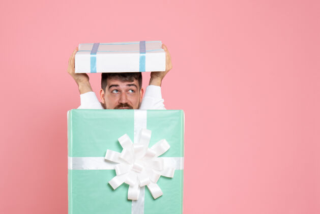 游戏前视图年轻男性试图隐藏在礼物盒内的粉红色圣诞色情感睡衣派对游戏前面颜色容器