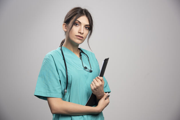 工作女医生拿着灰色的剪贴板检查妇女疾病