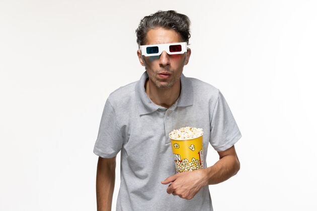 光学仪器正面图年轻男性戴着d型太阳镜在白色表面吃爆米花爆米花男眼镜