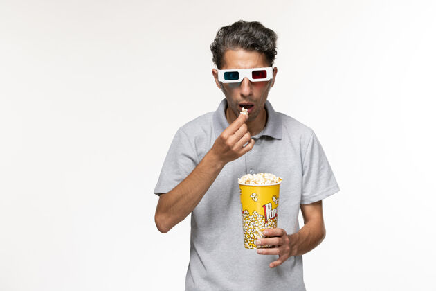 酒精正面图年轻男性戴着d型太阳镜在白色表面吃爆米花电影院太阳镜男