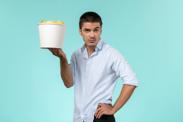 电影正面图：年轻的男性拿着蓝面薯片的篮子篮子年轻的男土豆