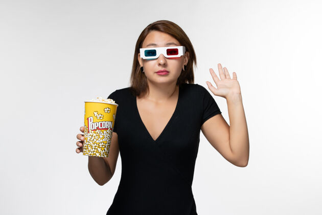电影院正面图戴着d型太阳镜拿着爆米花的年轻女性在白色表面看电影爆米花电影电影