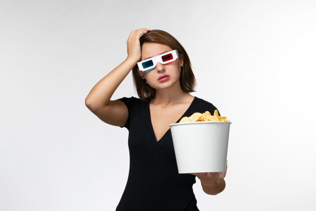 电影正面图年轻女性戴着d型太阳镜拿着薯片 在白色表面看电影土豆电影看