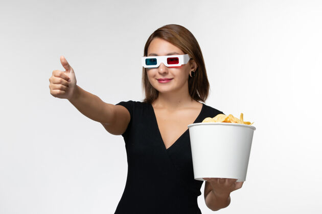 电影正面图年轻女性戴着d型太阳镜拿着薯片 在白色表面微笑着看电影电影漂亮孤独
