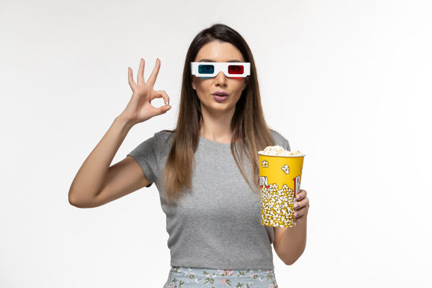 年轻的女性正面图年轻女性手持爆米花 戴着d墨镜在白色表面看电影持有女性孤独