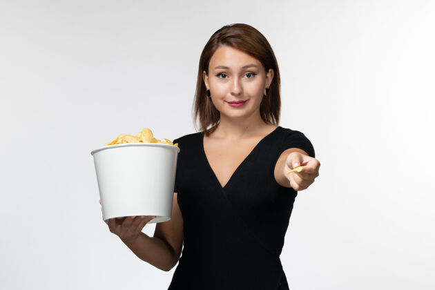 电影院正面图年轻的女性拿着篮子和薯片在浅白的表面上吃土豆孤独前面