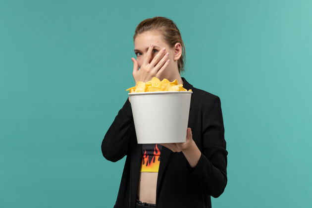 企业家前视图年轻女性吃薯片看电影在淡蓝色的表面电影前台年轻女性