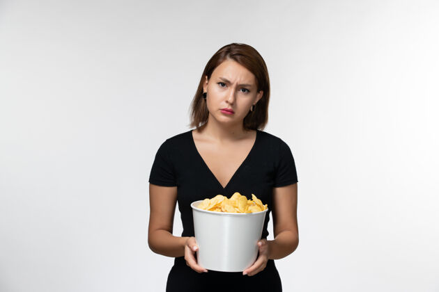 电影院正面图：年轻的女性拿着薯片 在白色的桌子上看电影容器土豆杯子