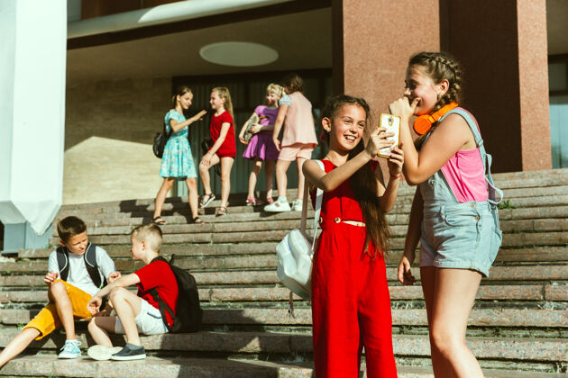 团体在阳光明媚的夏日 快乐的孩子们在城市的街道上玩耍 在现代化的建筑前微笑女孩孩子