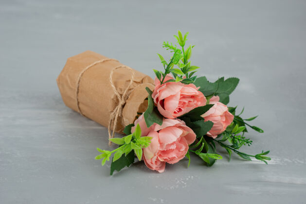 花束在灰色的桌子上放着一束美丽的粉红玫瑰叶玫瑰安排