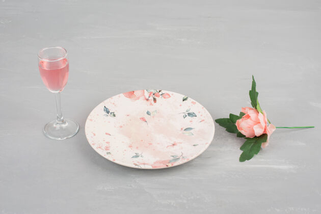 单身鲜花 盘子和一杯玫瑰红酒放在灰色的表面上婚礼玫瑰花