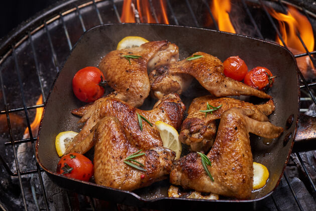 烤烤鸡翅在火焰烤架上 配烤蔬菜和胡椒籽 迷迭香 盐食物西红柿香草