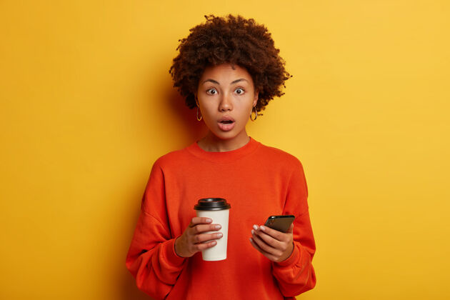 尴尬震惊的少数民族妇女在智能手机上收到令人震惊的信息咖啡惊讶非洲裔
