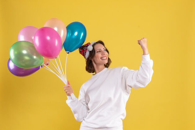 颜色正面图年轻靓女手持气球上黄色圣诞新年感慨的女人欢呼吹情绪