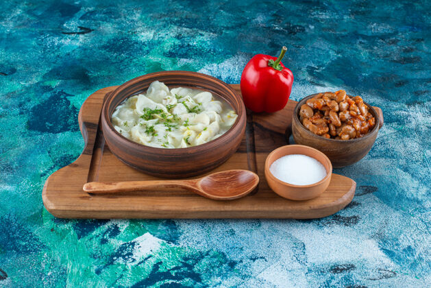烘焙烤豆子 杜什巴拉 勺子 胡椒粉和盐在一块板上 在蓝色的背景上美味碗杜什巴拉