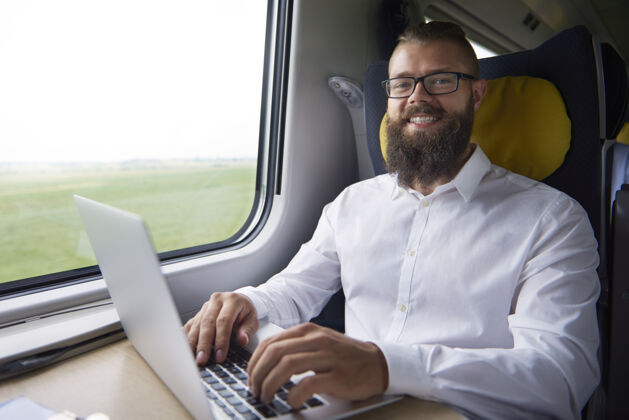 坐着在火车上工作的年轻人的画像乘客胡须微笑