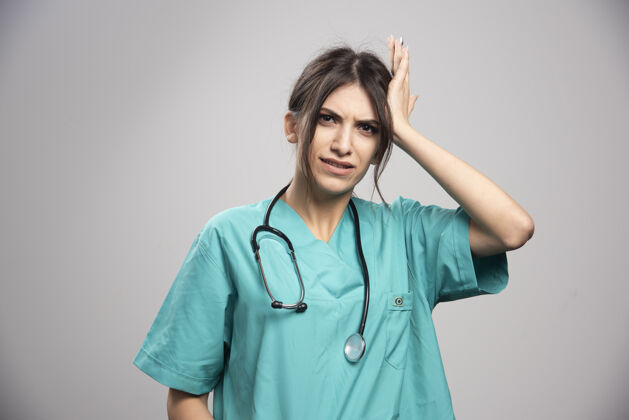 听诊器穿制服的女医生把头靠在灰色的衣服上妇女成人医生