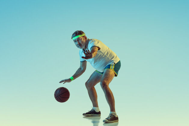 设备资深男子在霓虹灯下的斜坡墙上打篮球球拍动作休闲