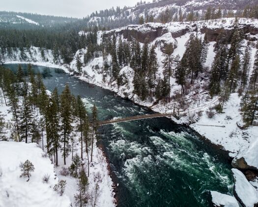 春天高角度拍摄的一条河在雪山的中间覆盖着树木景色山谷冬天