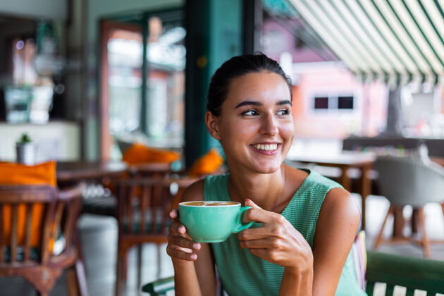 放松可爱 优雅 平静 快乐的女士 穿着绿色夏装 坐在咖啡馆里喝咖啡 享受早晨肖像杯子一