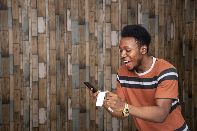 人年轻的非洲男性拿着他的智能手机和纸条感到兴奋在线非洲电话