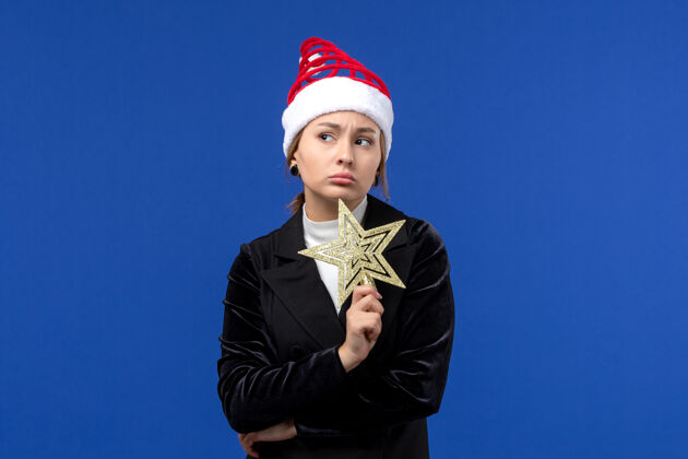 领带正面图：年轻女子手持星形玩具在蓝色墙壁上过年过节公司成功个人
