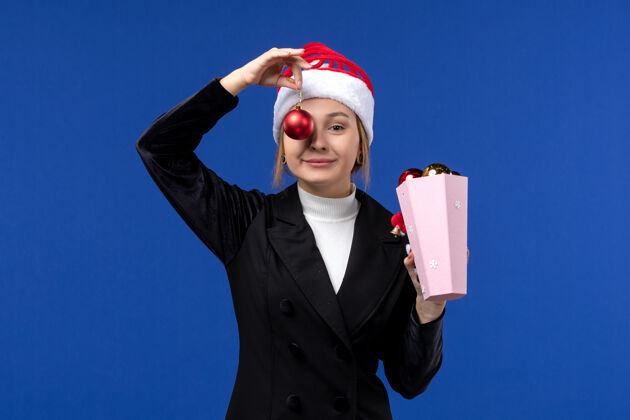 正面前视图年轻的女性拿着蓝色背景的圣诞树玩具蓝色情感新年假期圣诞节成功情绪